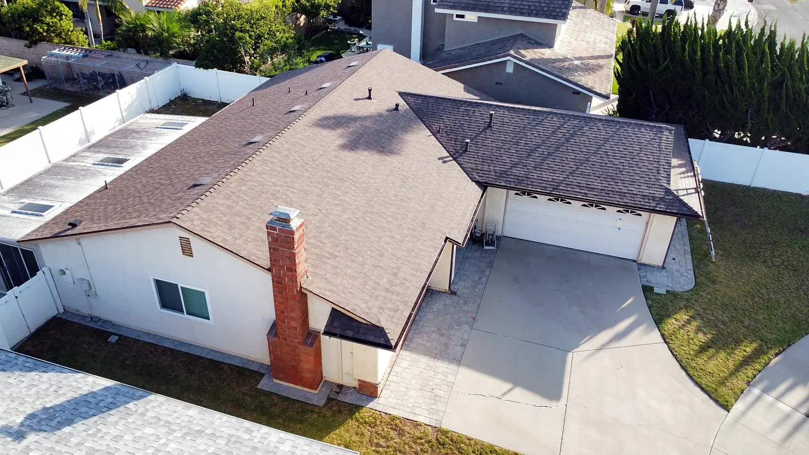 New light brown architectural shingle roof with brick chimney on an Oxnard, CA home after roof replacement